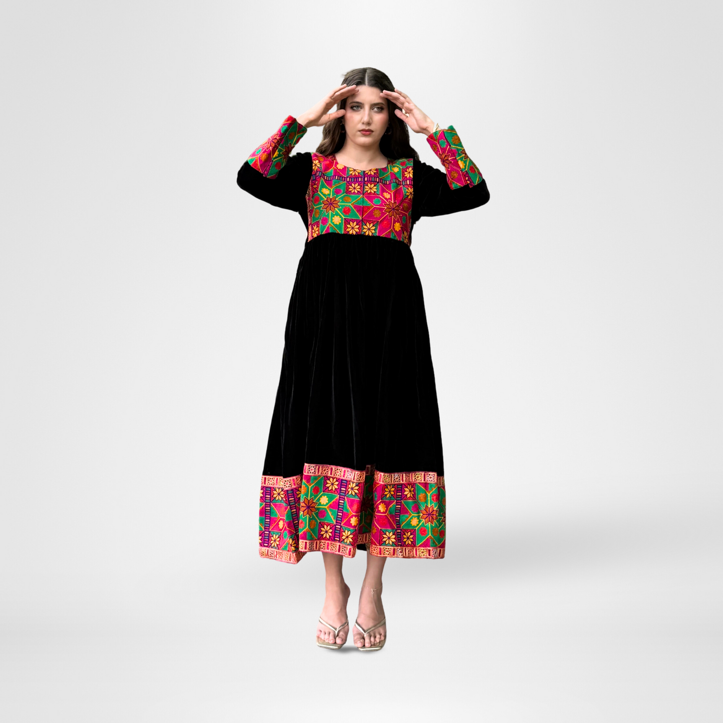 Woman wearing a black traditional dress with colorful embroidery in red, green, pink, and gold, Noorani.