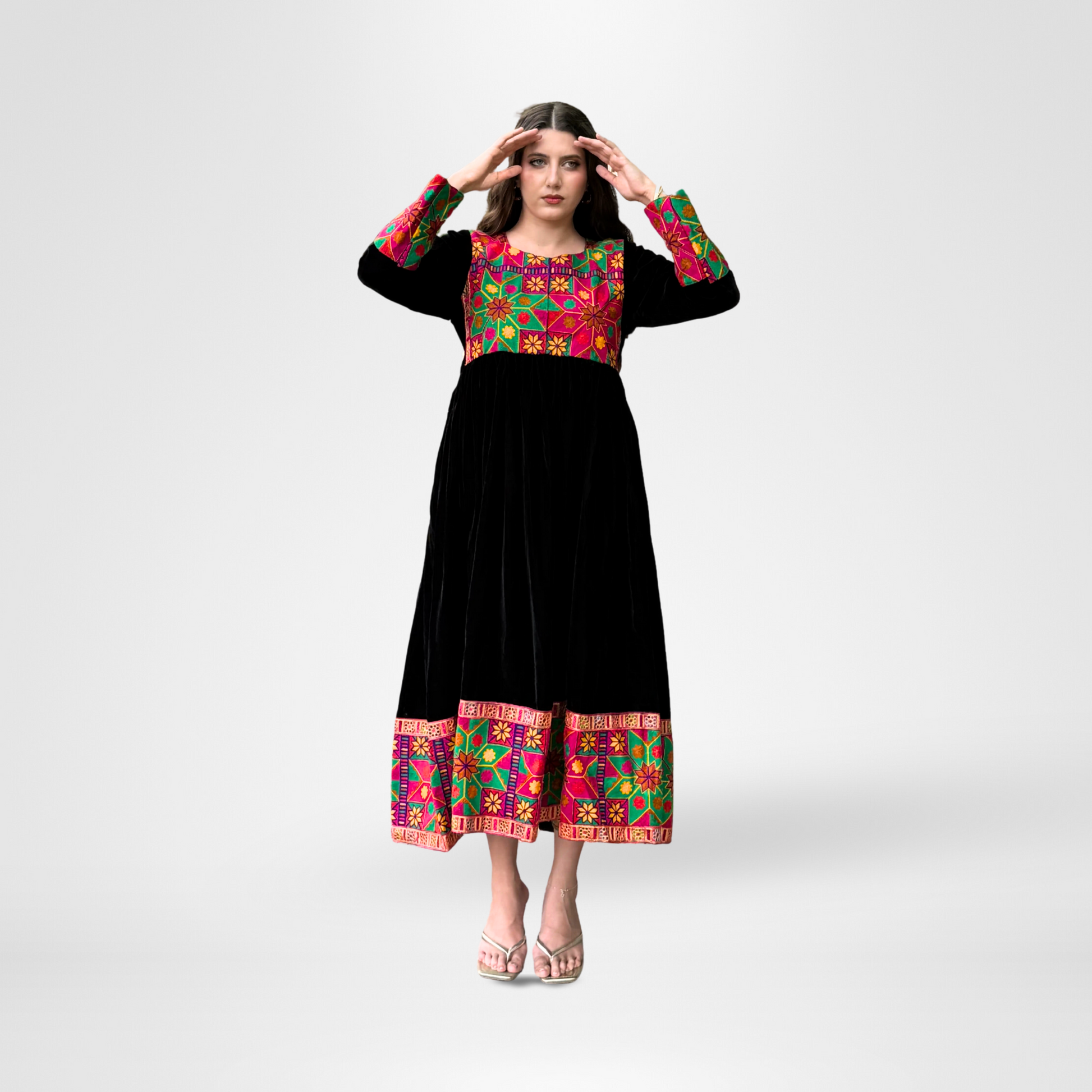 Woman wearing a black traditional dress with colorful embroidery in red, green, pink, and gold, Noorani.