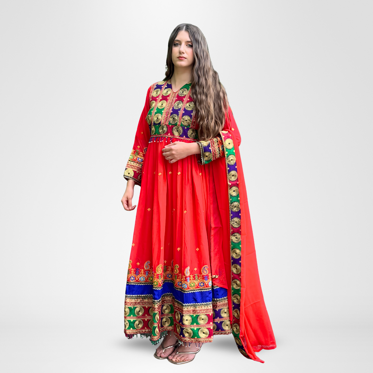 Woman wearing a red traditional dress with colorful embroidery and mirror work in gold, green, blue, and multicolored patterns on the bodice, sleeves, and hem, Rang Mahal.